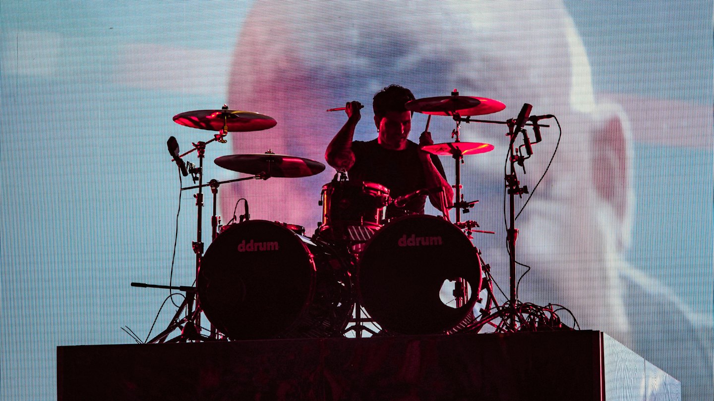 Drummer geeft een muzikaal optreden op een verlicht podium.