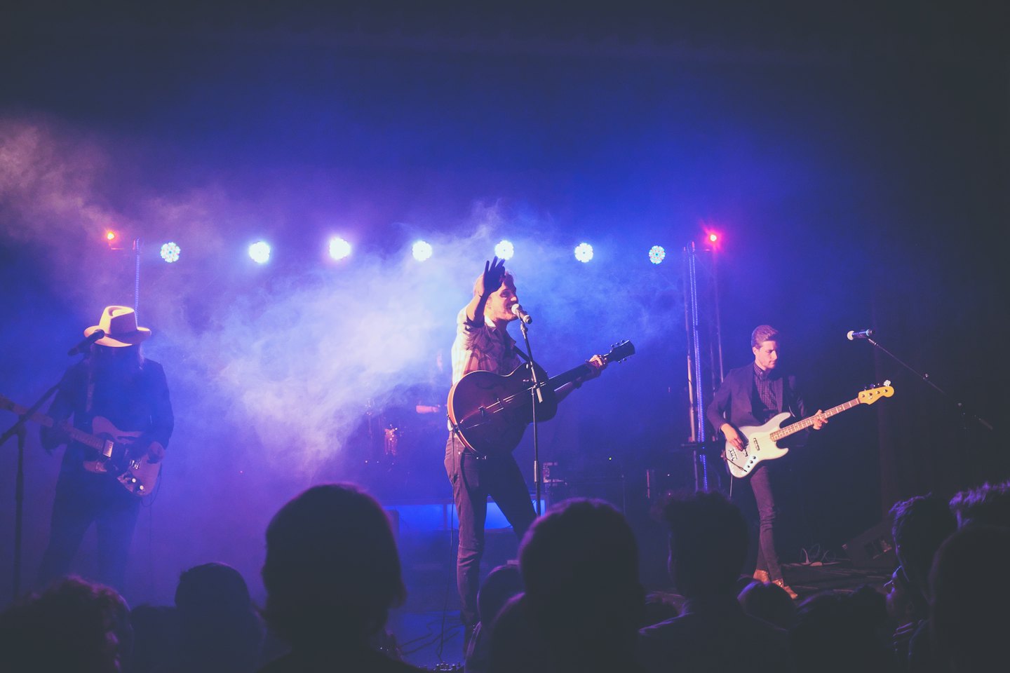 Band treedt live op met blauwe en paarse podiumverlichting.