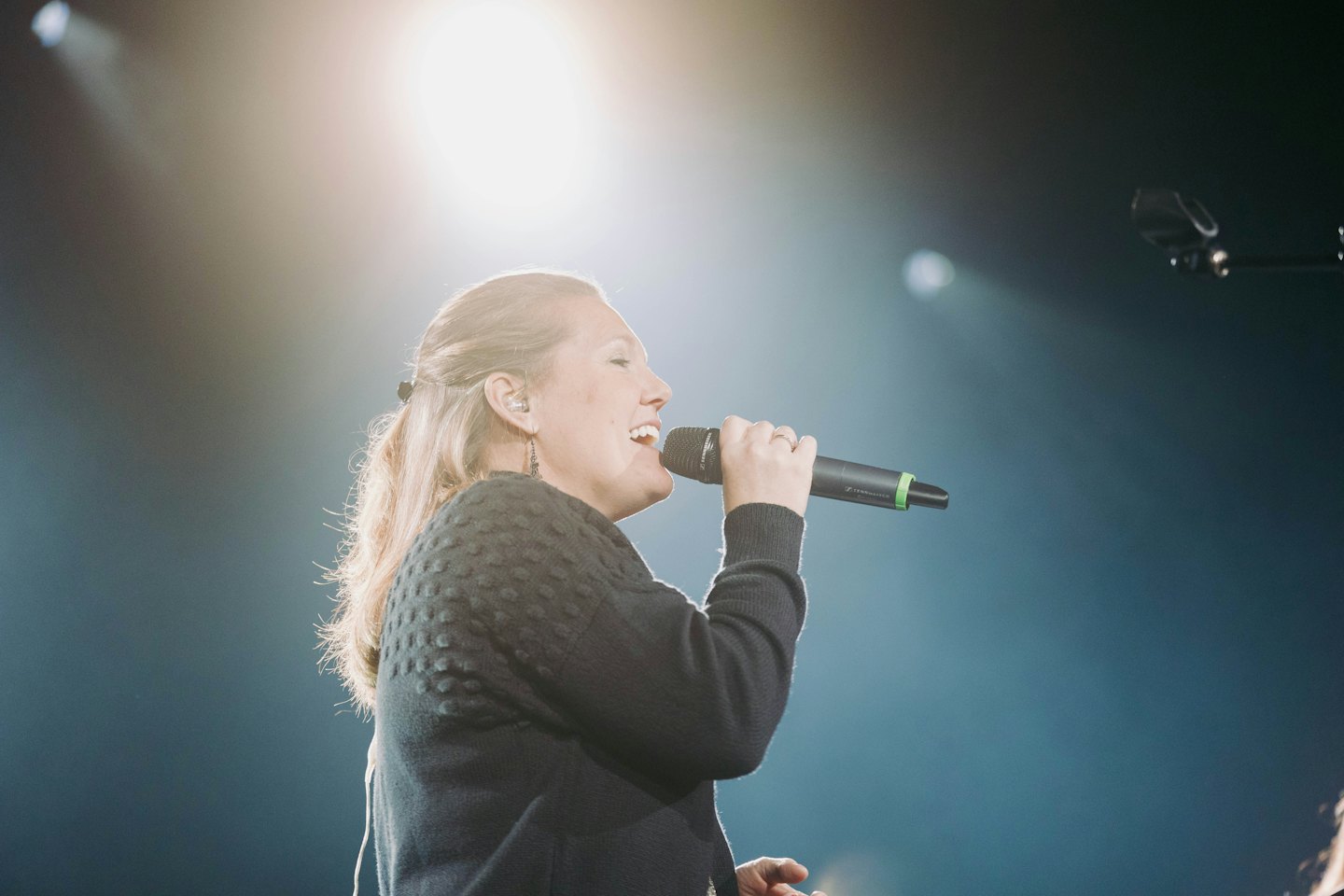 Een vrouw die op een podium in een microfoon zingt.